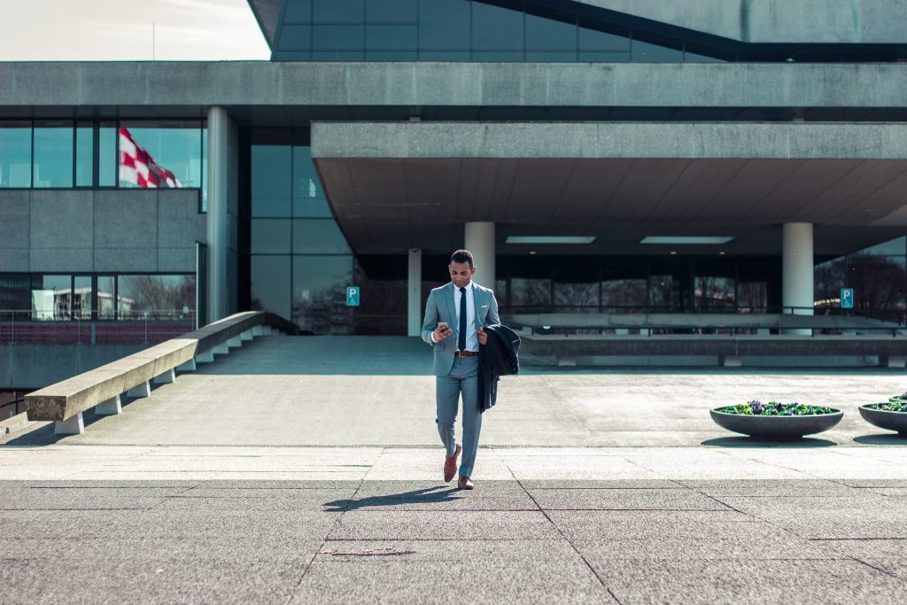 business man in gray suit with brief case walking outside building